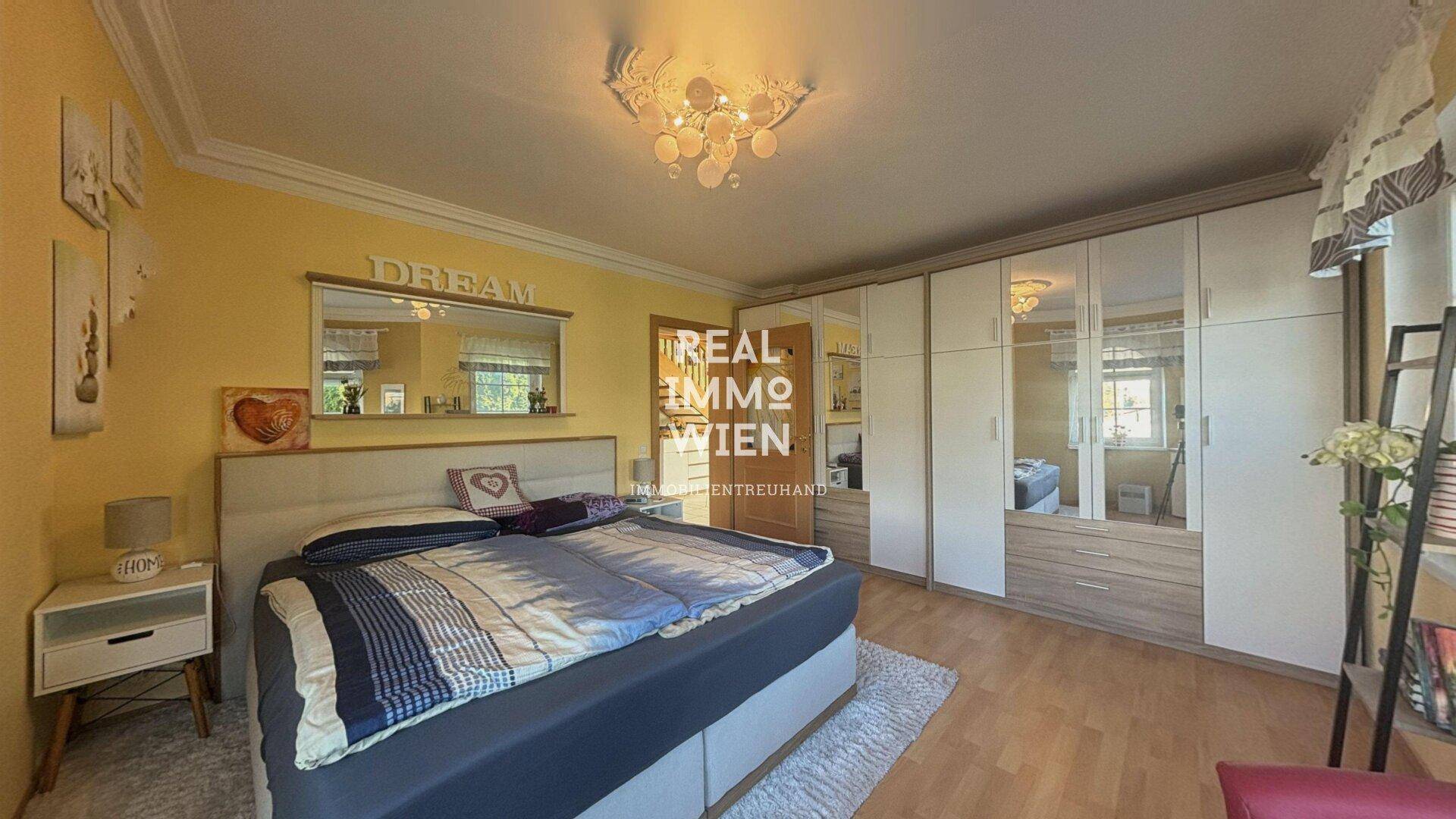 Gemütliches Schlafzimmer mit Doppelbett, Spiegelschränken und Parkettboden.