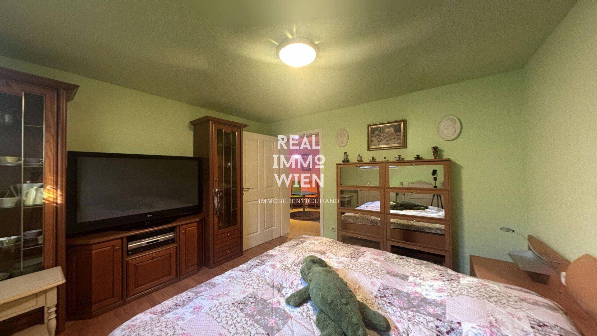 Schlafzimmer mit Doppelbett, Kleiderschrank und grün gestrichenen Wänden.