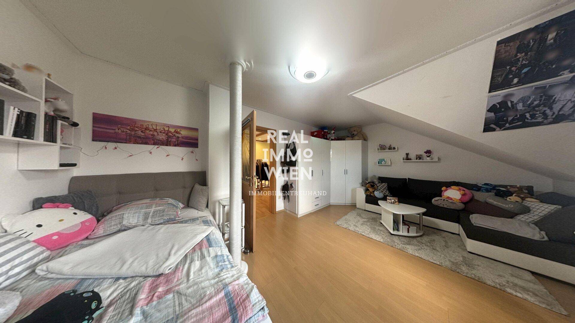 Dachgeschosszimmer mit Schlafbereich, Sitzecke und Dachschräge.