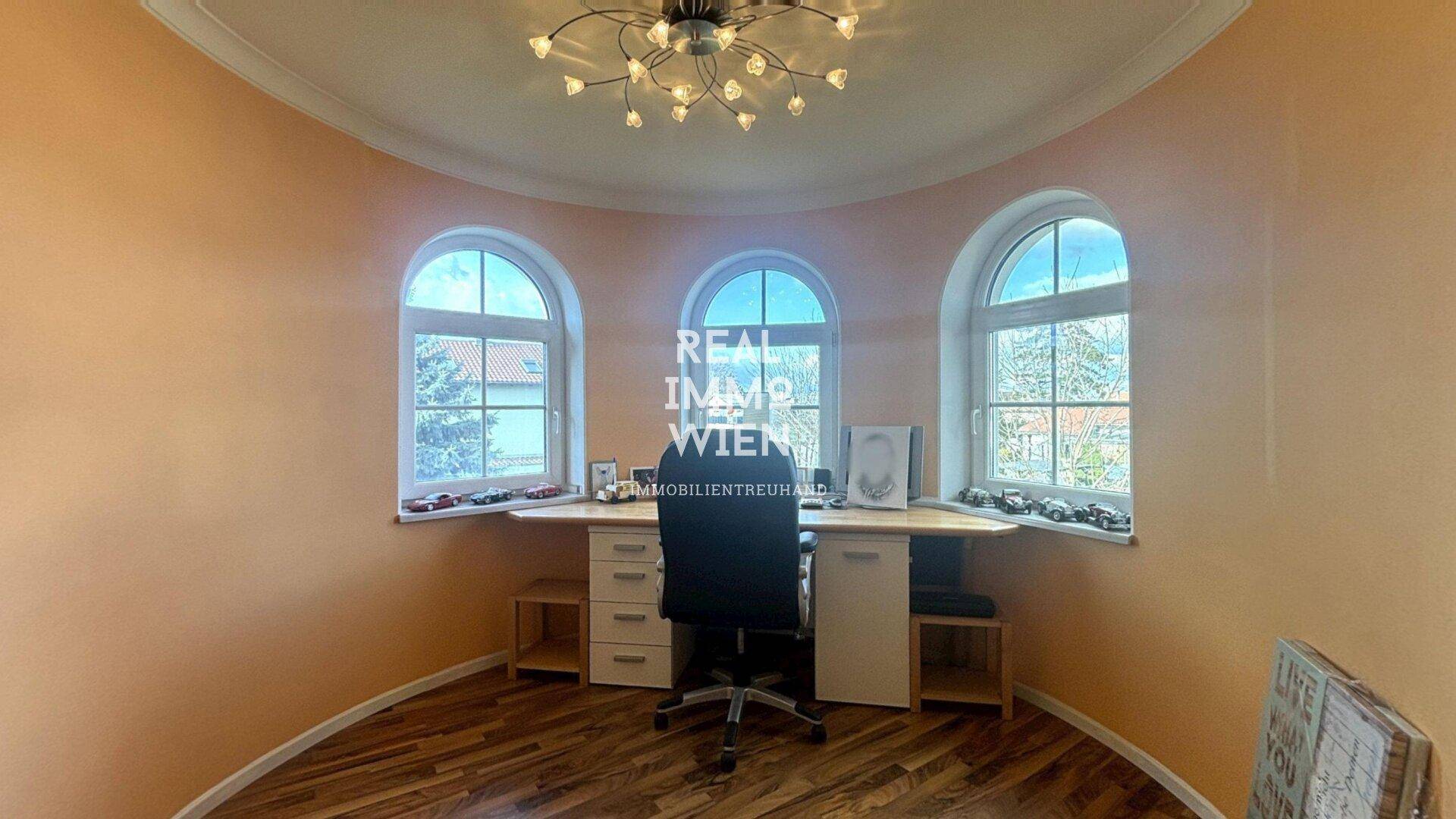 Rundes Arbeitszimmer im Turm mit drei Fenstern und Holzboden.