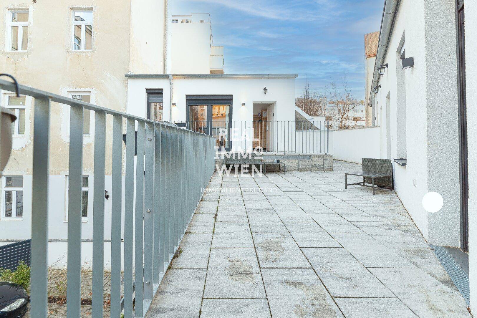 Geräumige Dachterrasse mit Fliesenboden und Blick auf umliegende Gebäude.