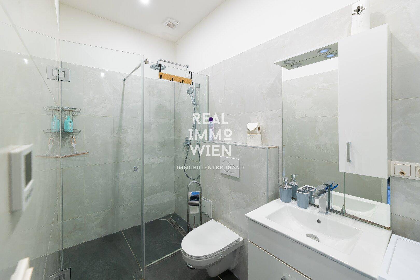 Modernes Badezimmer mit großer Glasdusche, Wand-WC und eleganten Fliesen.