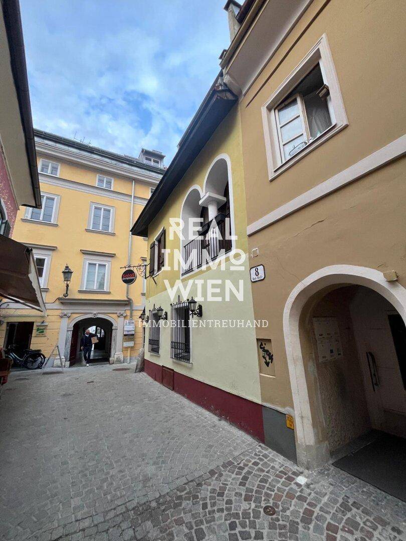 Historische Gasse mit gelben Gebäuden, gewölbten Durchgängen und traditioneller Architektur.