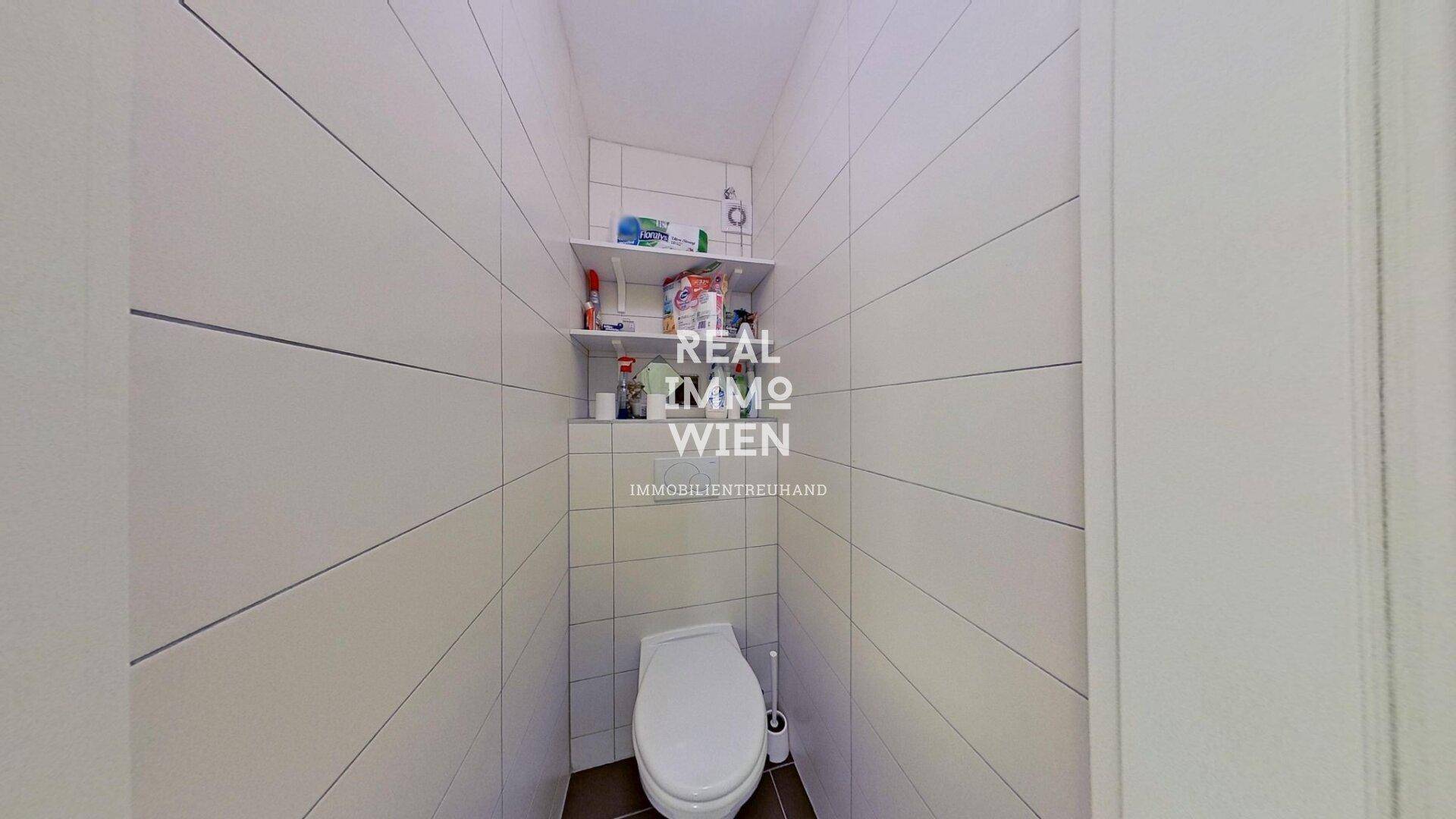 Separates WC mit Wandfliesen und einer einfachen Toilette.