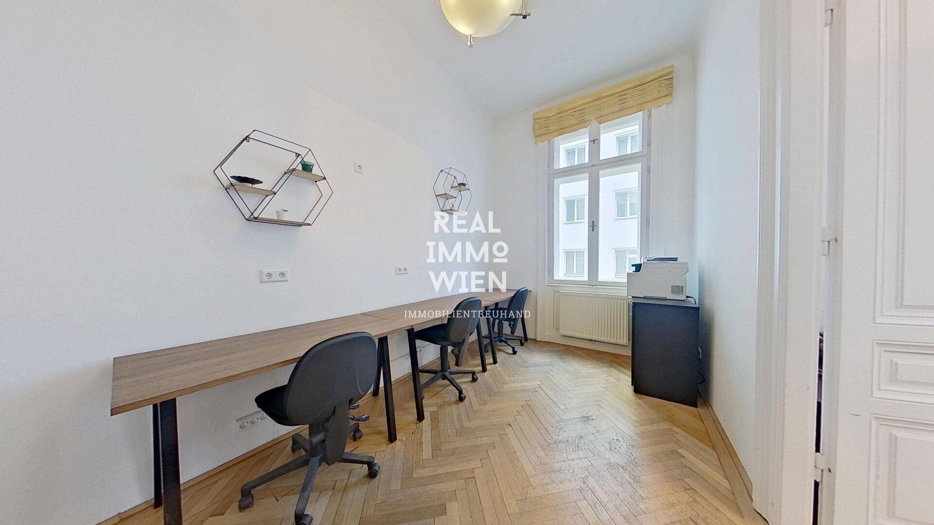 Langer Büroraum mit mehreren Arbeitsplätzen entlang einer Wand, Fischgrätparkett und einem Fenster.