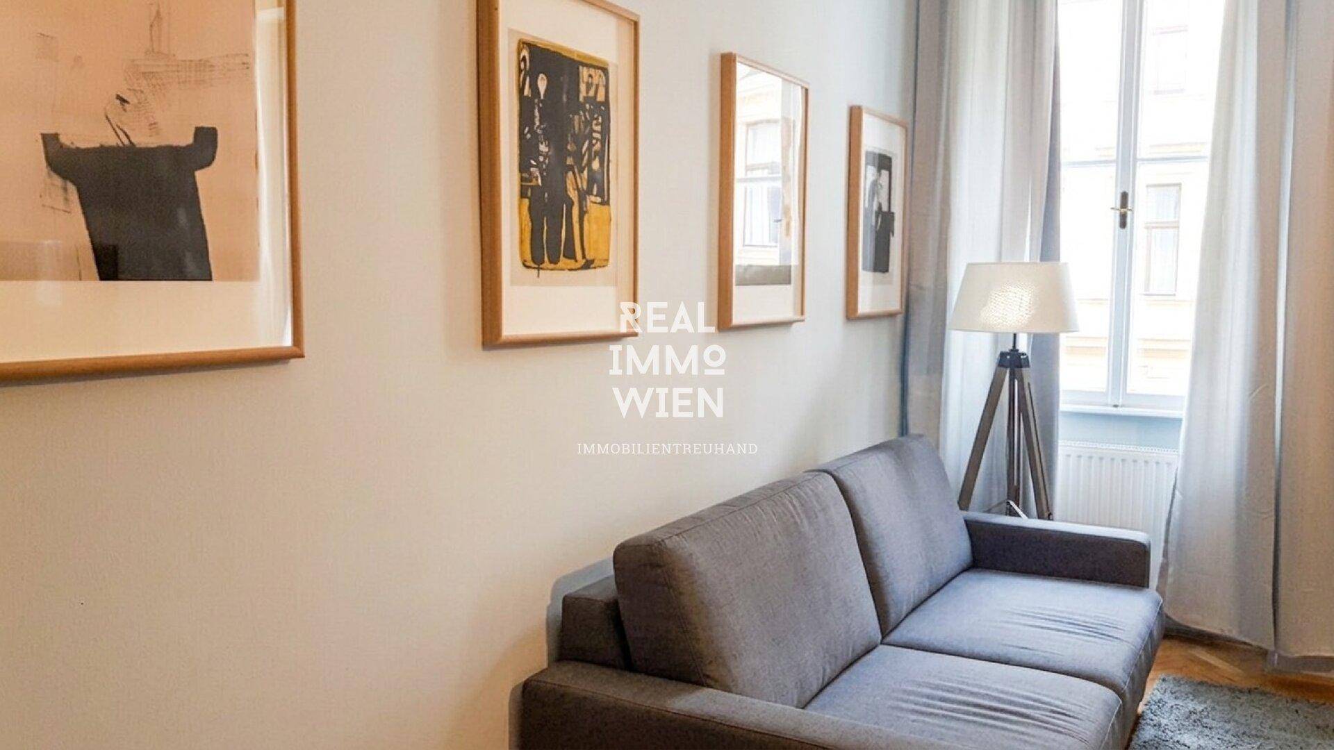 Gemütliches Wohnzimmer mit grauem Sofa, Stehlampe und Kunstwerken an der Wand, mit Blick nach draußen.