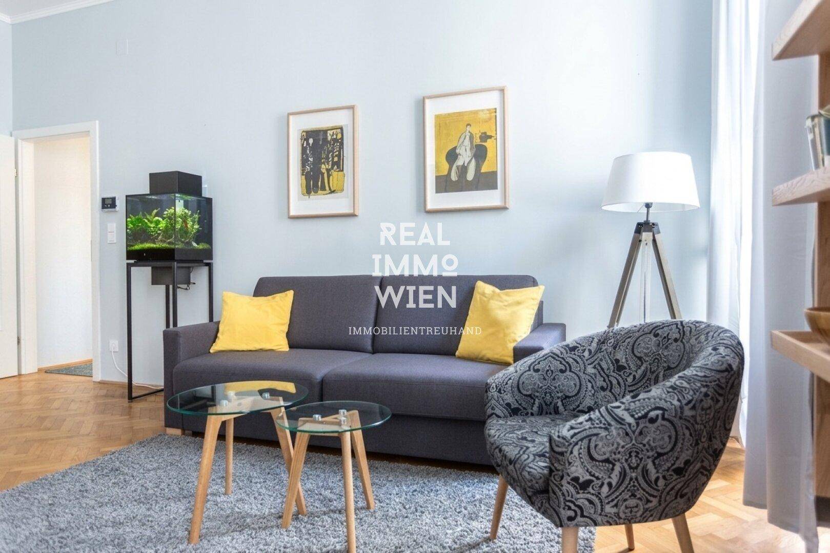 Wohnzimmer mit bequemer Couch, Sessel, Couchtischen und einem Aquarium, das eine entspannte Atmosphäre schafft.