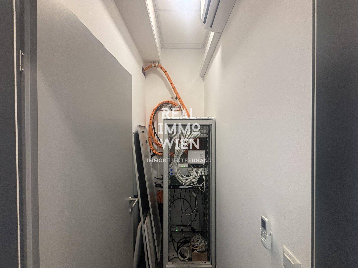 Technikraum mit Serverschrank, Verkabelung und Klimaanlage für optimale Kühlung.