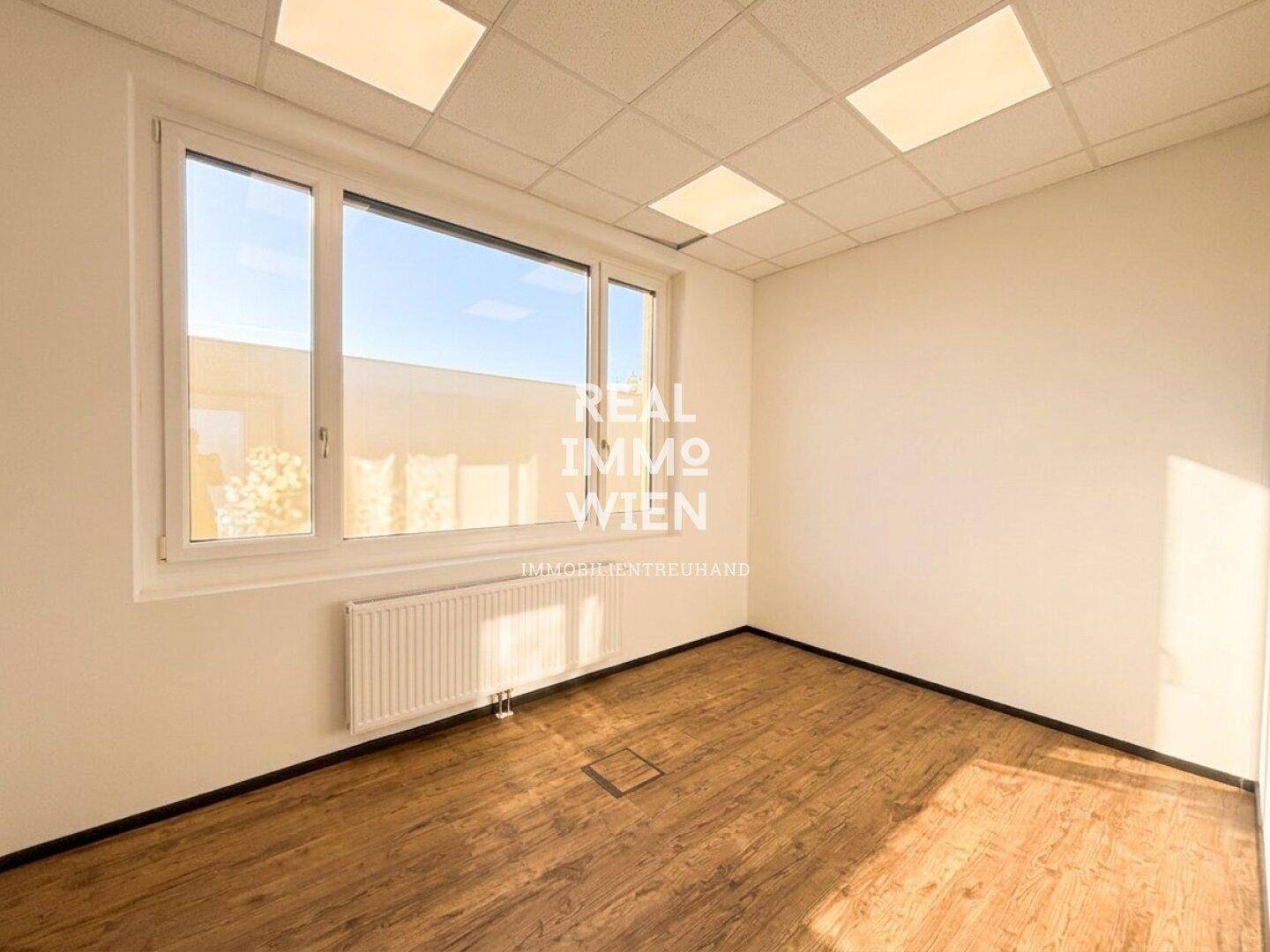 Kleineres Büro mit einem großen Fenster, das viel Sonnenlicht in den Raum bringt.
