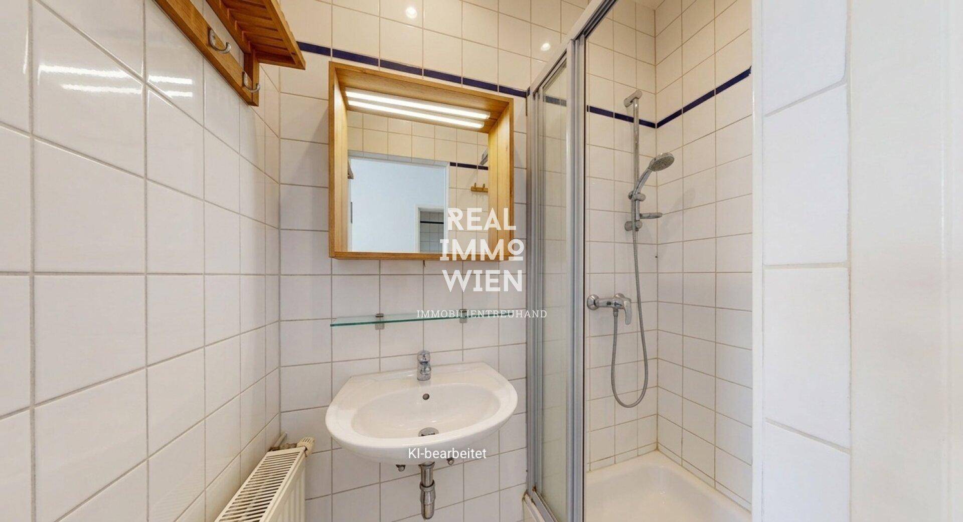 Kleines Badezimmer mit weißen Fliesen, Waschbecken, Spiegelschrank und Duschkabine.
