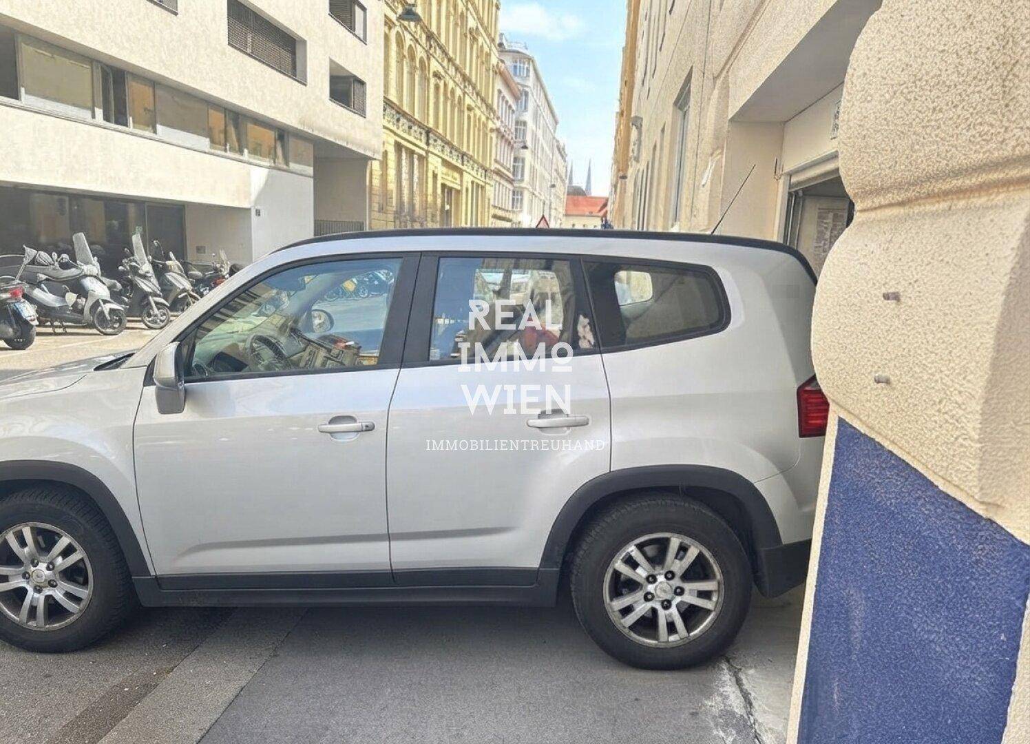 Ein Auto parkt am Straßenrand in einer städtischen Umgebung mit Gebäuden im Hintergrund.