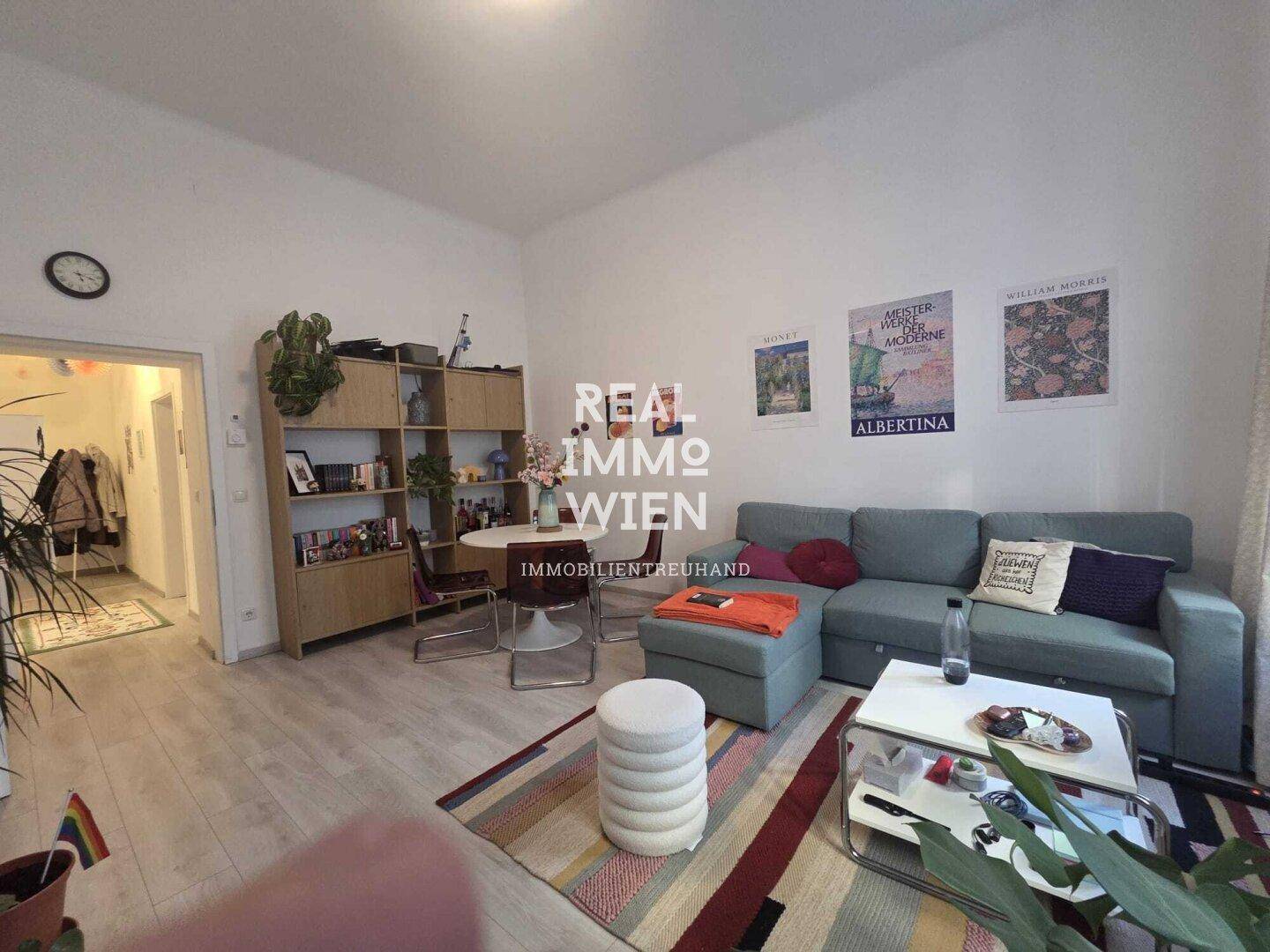 Gemütlicher Wohnbereich mit Sofa, Esstisch und Bücherregal, mit hellem Laminatboden.