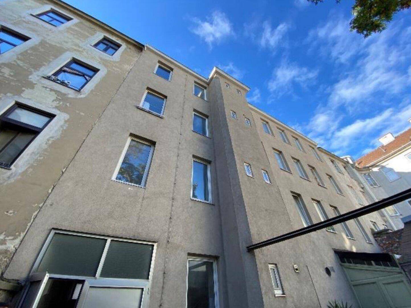 Seitenansicht des Gebäudes mit mehreren Fenstern und einem klaren blauen Himmel.