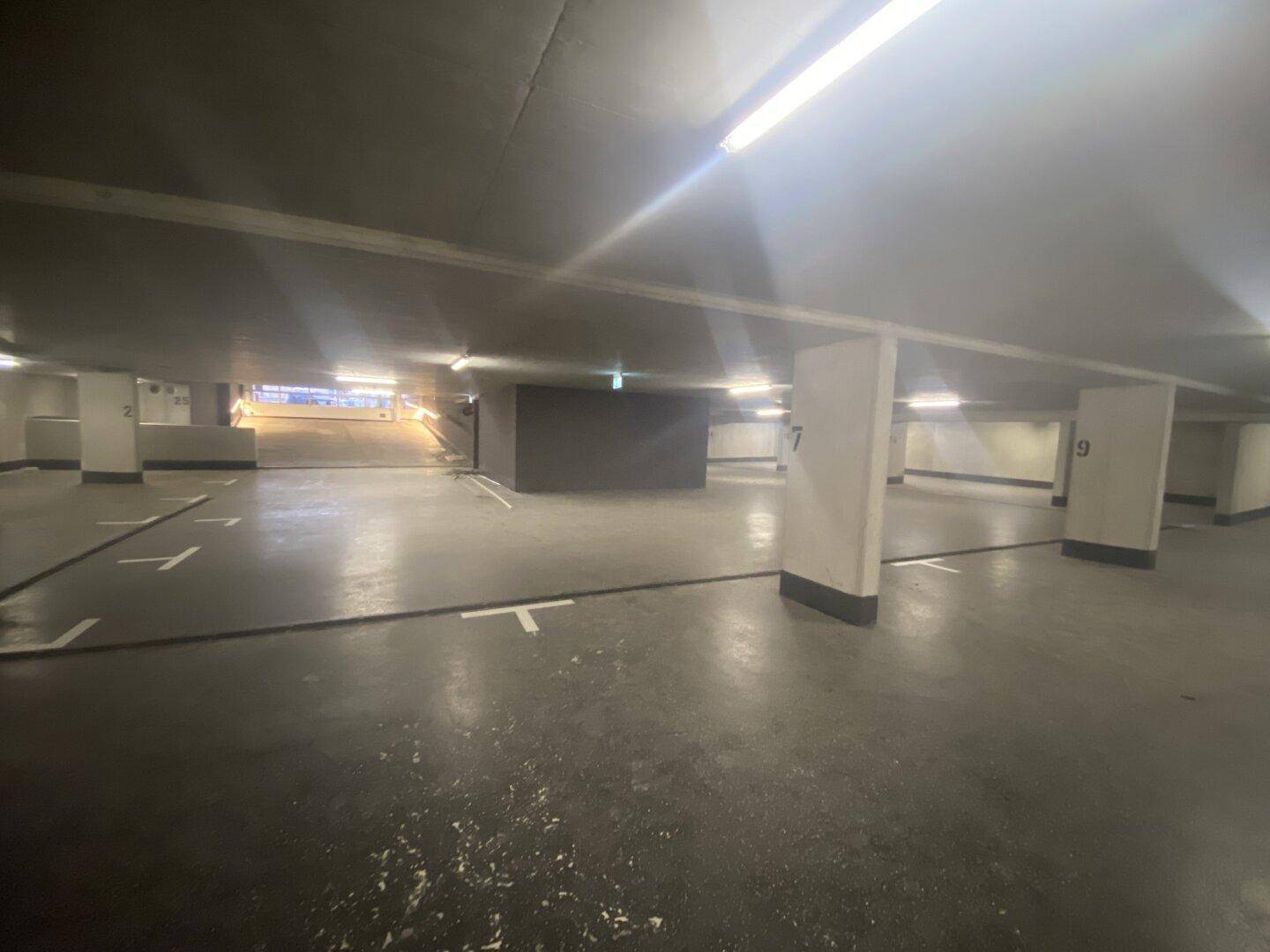 Geräumige Tiefgarage mit mehreren Stellplätzen und guter Beleuchtung im Untergeschoss.