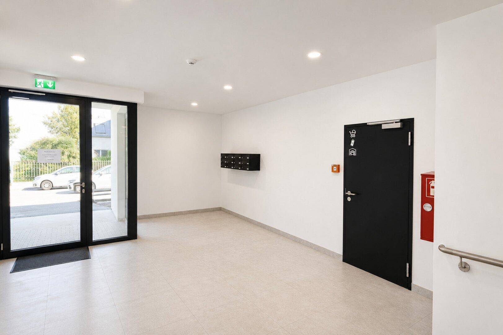 Heller Eingangsbereich eines Mehrfamilienhauses mit Fliesenboden und Briefkästen.