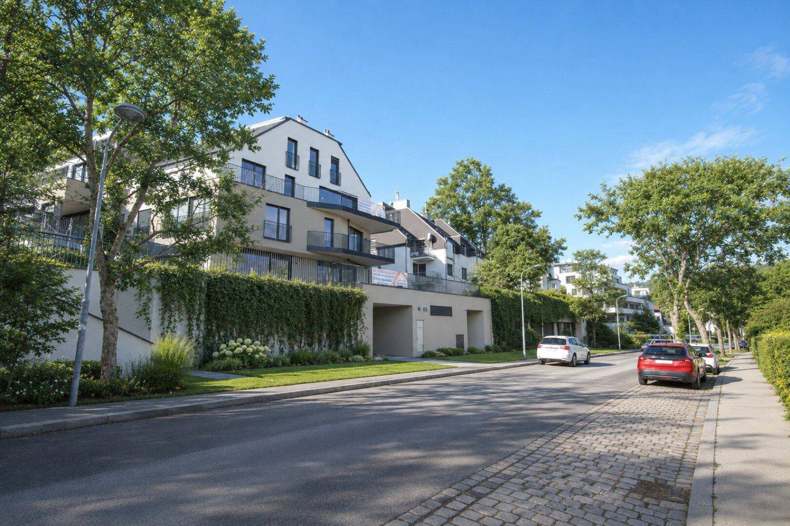 Moderne Wohngebäude mit Balkonen und begrünten Fassaden entlang einer ruhigen Wohnstraße.