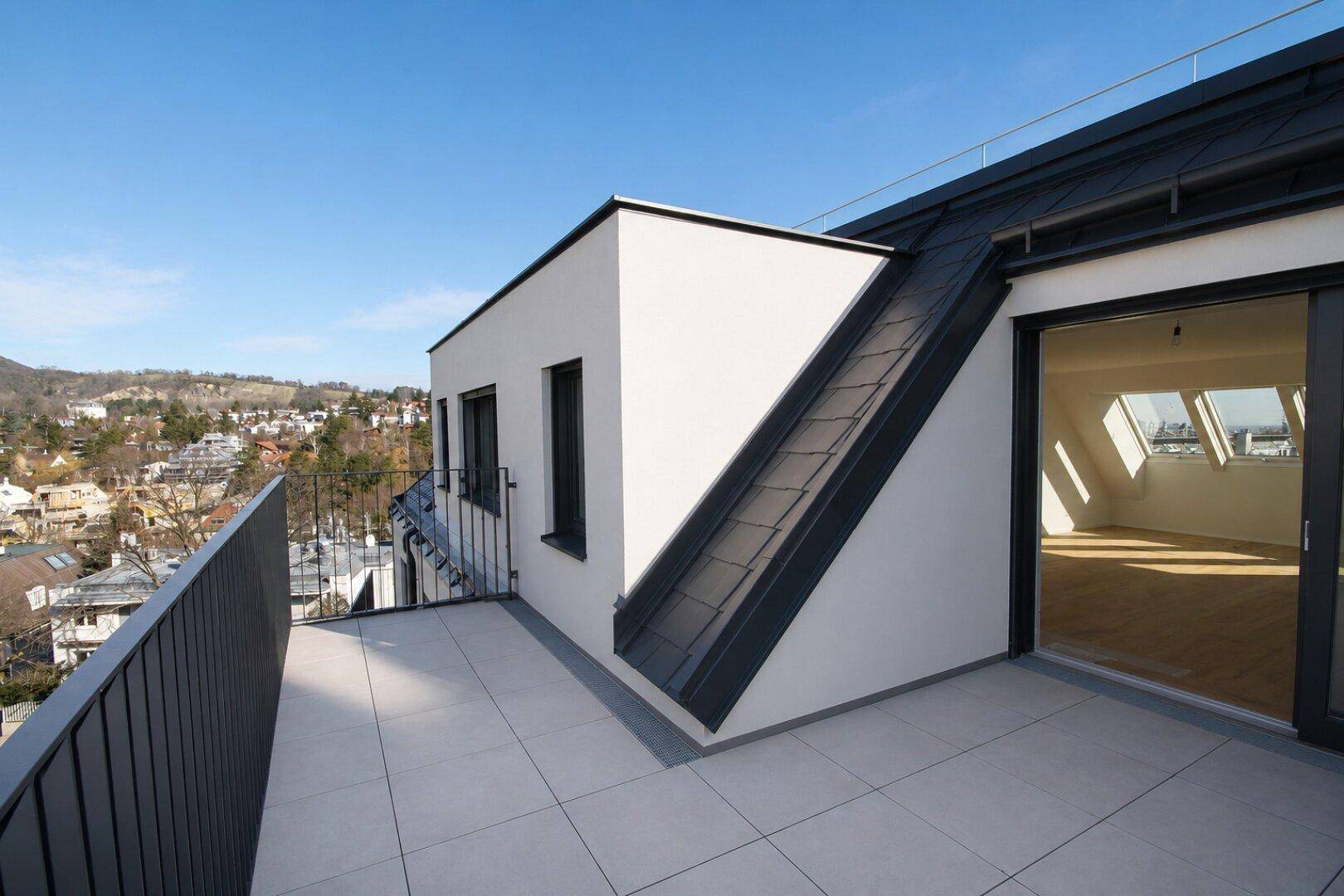 Geräumige Dachterrasse mit Fliesenboden und weitem Blick über die Stadt und die umliegenden Hügel.