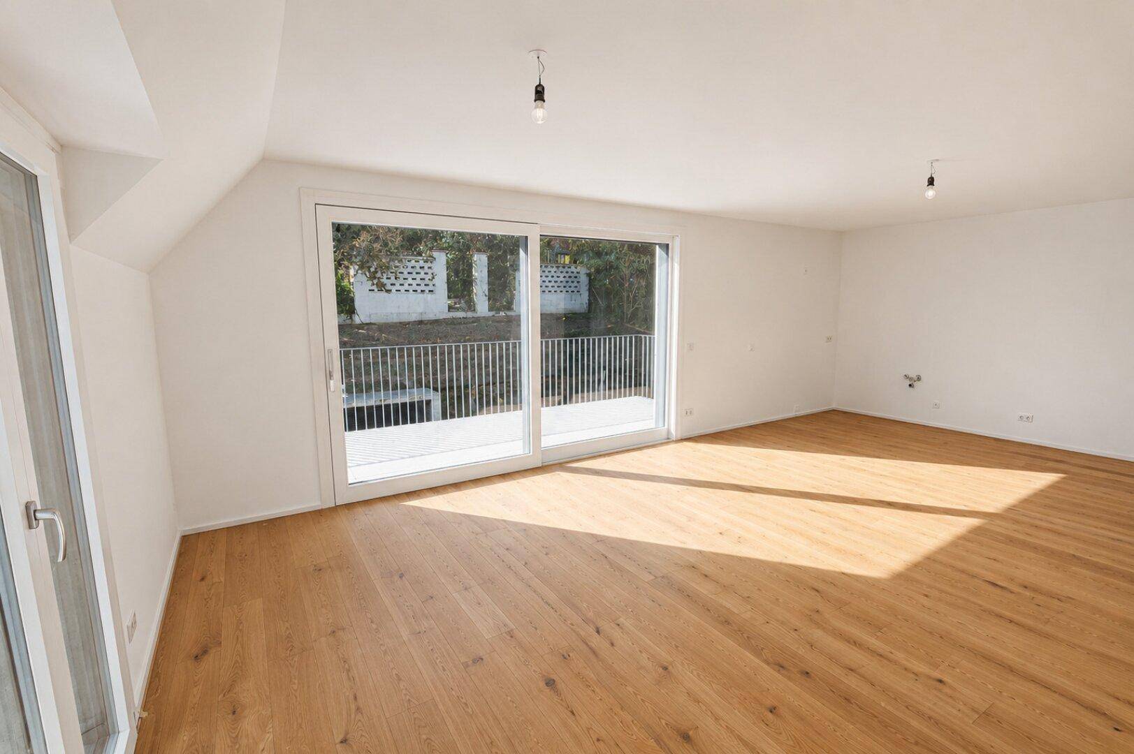 Geräumiger, heller Wohnraum mit Holzboden und großen Schiebetüren zum Außenbereich.