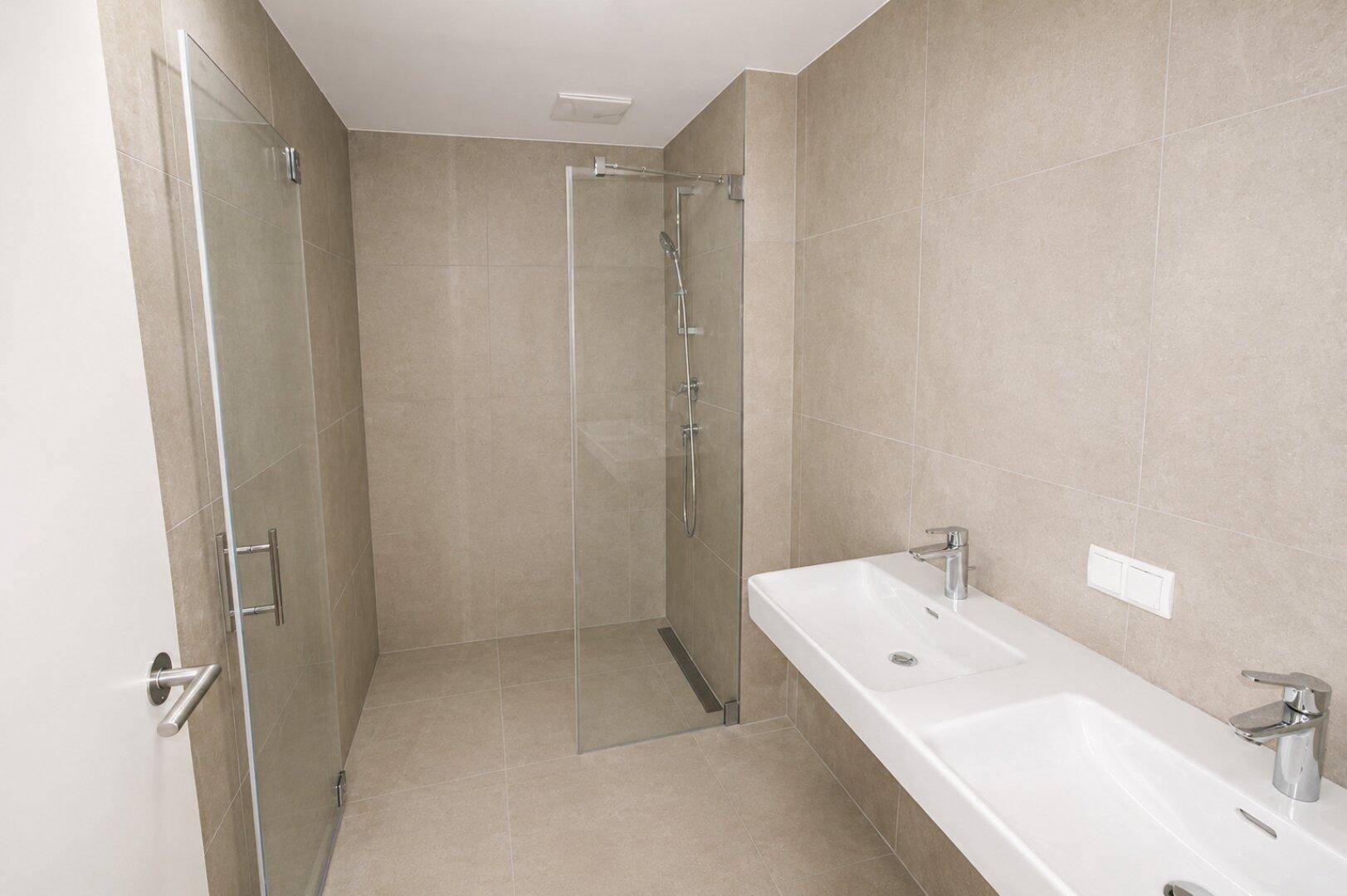 Modernes Badezimmer mit doppelten Waschbecken und einer geräumigen begehbaren Dusche.