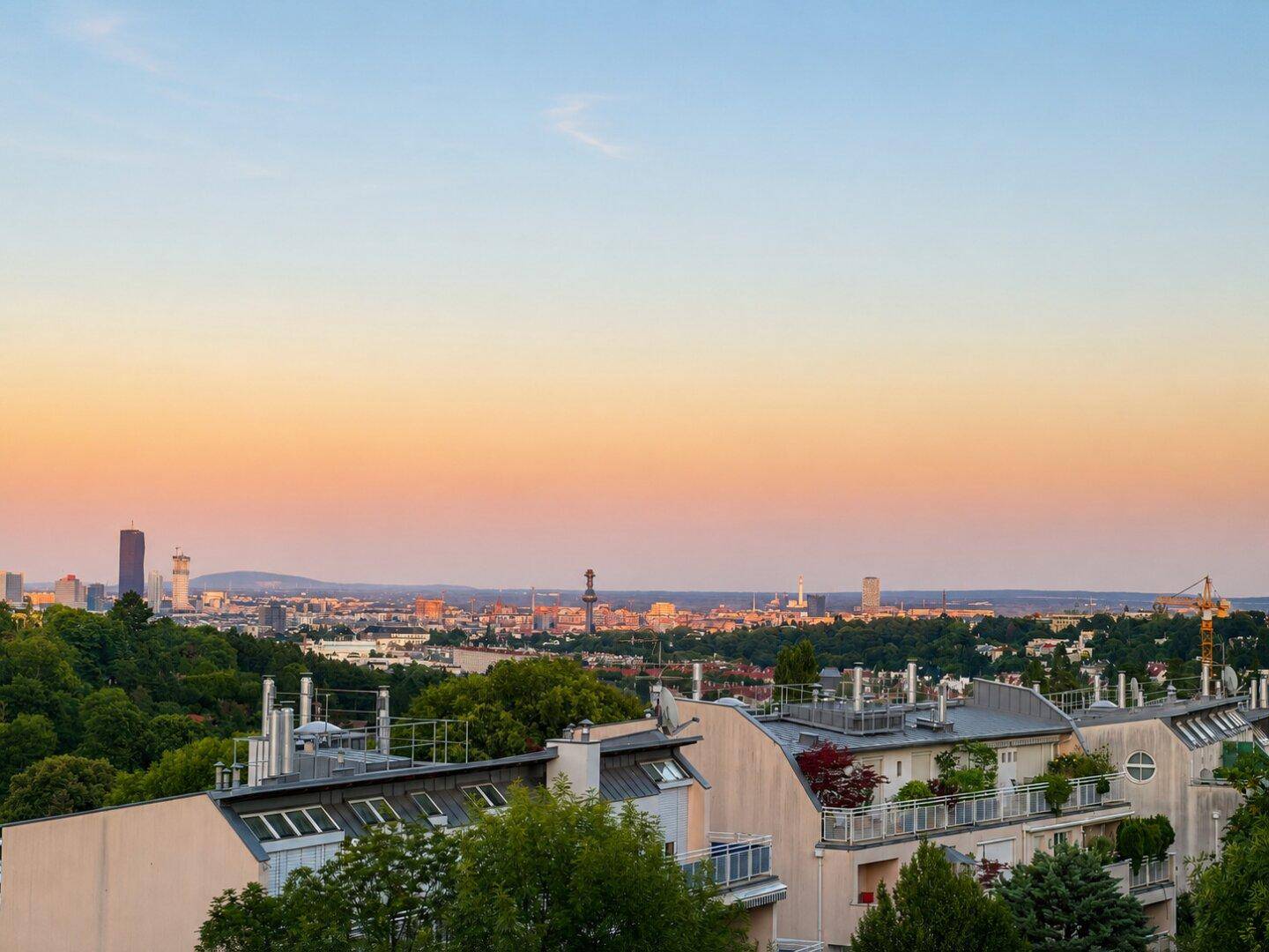 Panoramablick auf die Stadt bei Sonnenuntergang mit Wohngebäuden im Vordergrund.