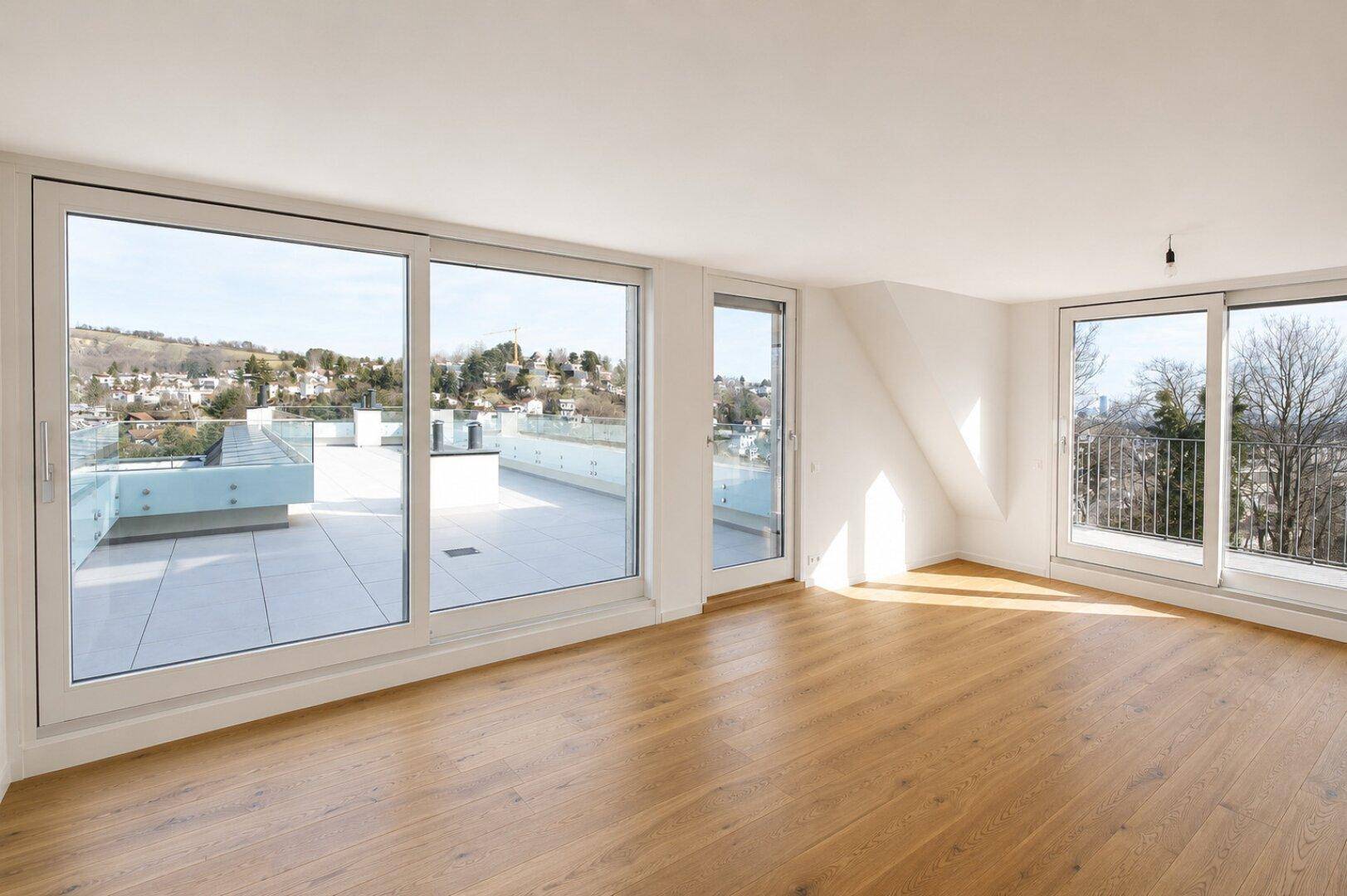 Heller Wohnraum mit Holzboden, großen Fenstern und Zugang zur Dachterrasse.