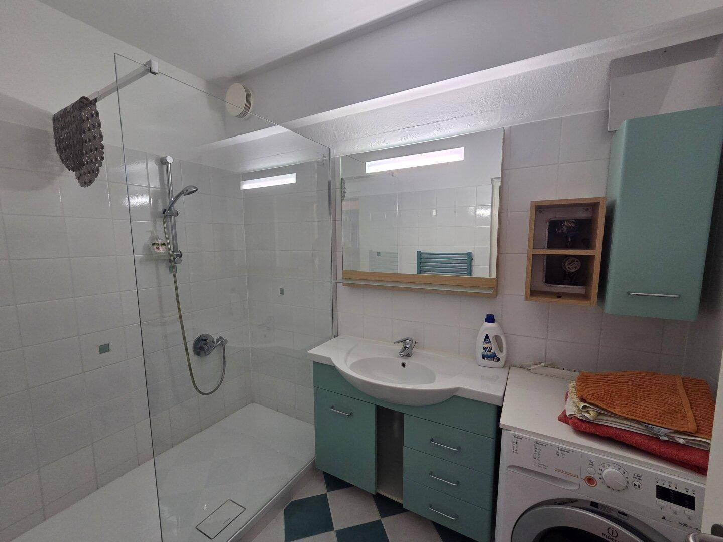 Modernes Badezimmer mit ebenerdiger Dusche, Waschbecken und Waschmaschine.