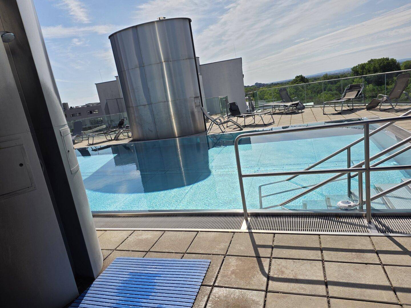 Dachterrasse mit einem Außenpool, Liegestühlen und einem weiten Blick über die Umgebung.