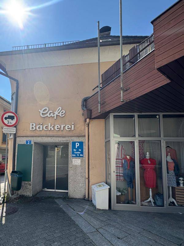 Eingangsbereich eines Cafés und einer Bäckerei mit Schaufenstern und Parkmöglichkeiten.