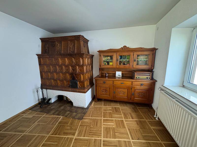 Wohnzimmer mit beeindruckendem, reich verzierten Kachelofen und klassischem Parkettboden.