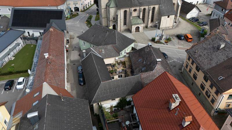 Weitläufige Luftaufnahme der Stadt mit vielen Dächern und einer historischen Kirche im Zentrum.
