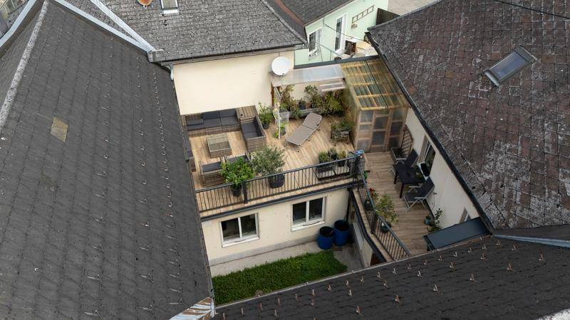 Detaillierte Luftaufnahme einer möblierten Dachterrasse mit Pflanzen und bequemen Sitzgelegenheiten.