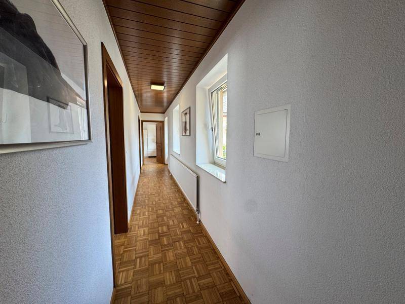 Langer Flur mit Holzdecke und Parkettboden, der zu weiteren Räumen im Haus führt.