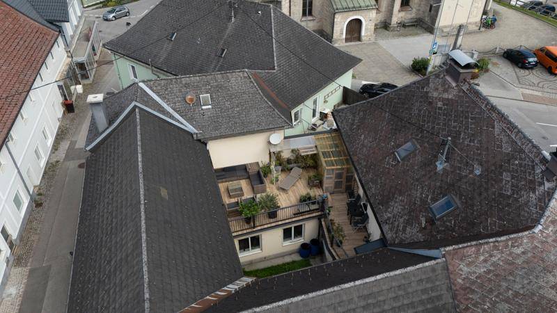 Luftaufnahme eines Innenhofs mit einer großen Terrasse, umgeben von Gebäudedächern.