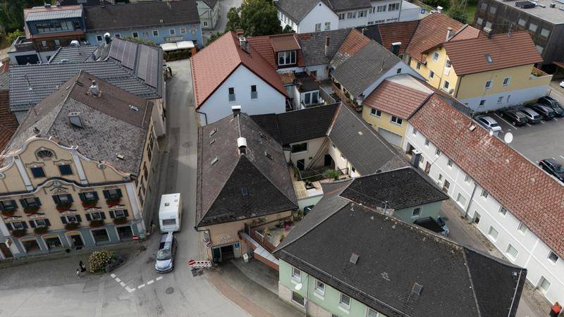 Luftaufnahme einer Wohnsiedlung mit verschiedenen Dächern und einem Wohnwagen auf der Straße.