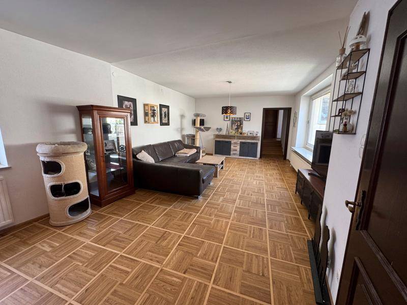 Geräumiges Wohnzimmer mit großem Ledersofa und klassischem Parkettboden, ideal für Entspannung.