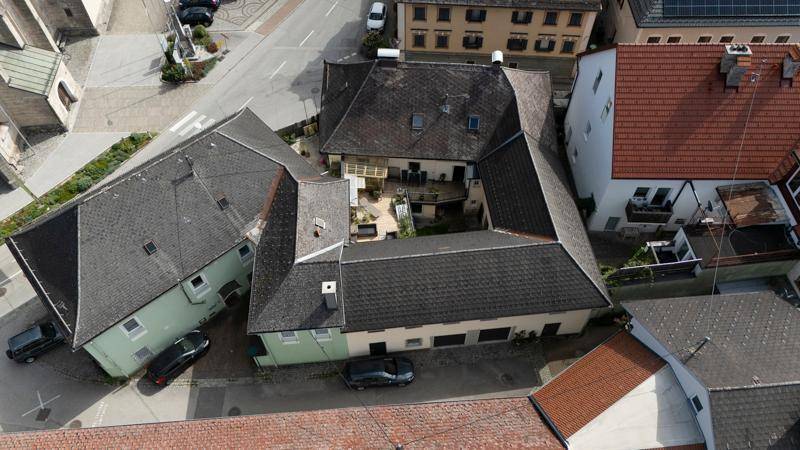 Luftaufnahme des Gebäudekomplexes mit zentraler Terrasse und den angrenzenden Häusern.