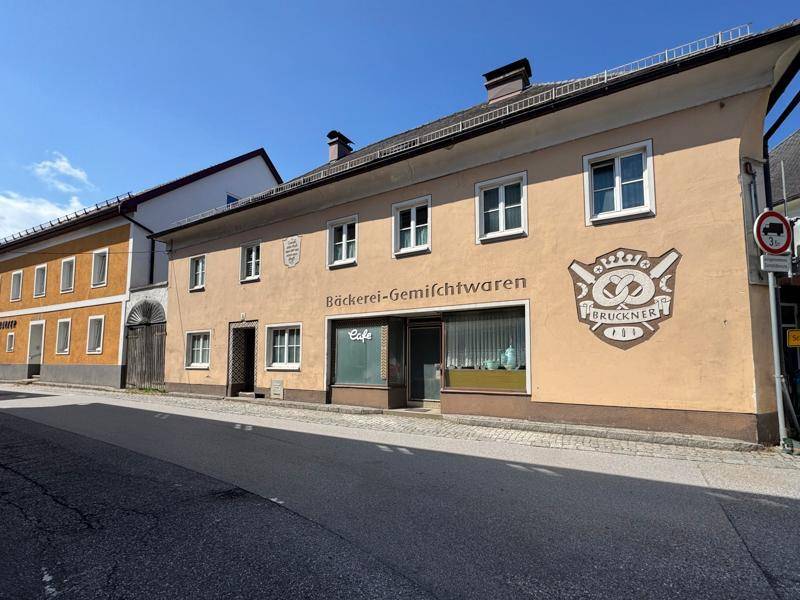 Fassade eines alten Gebäudes mit Bäckerei- und Gemischtwarenladen an einer belebten Straße.