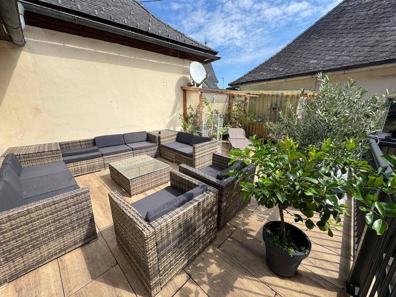 Geräumige Terrasse mit bequemen Loungemöbeln und Pflanzen, ideal zum Entspannen im Freien.
