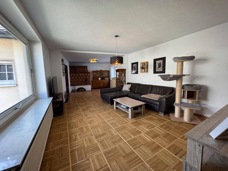 Weitläufiges Wohnzimmer mit viel Platz, Parkettboden und traditionellem Ambiente.