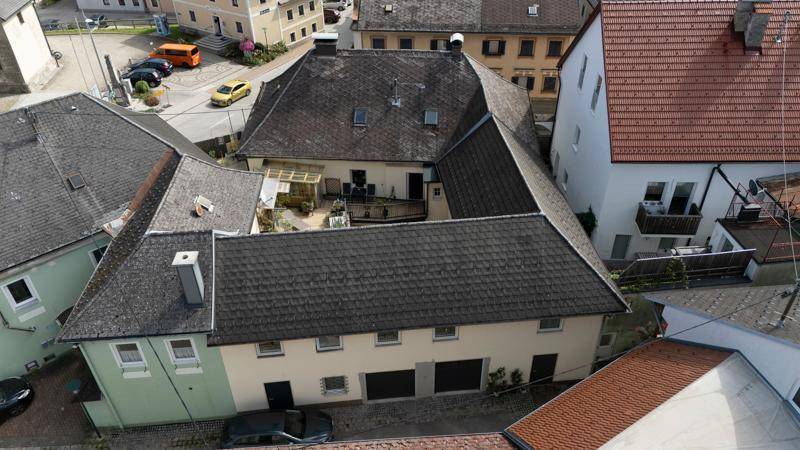 Luftaufnahme des Gebäudekomplexes mit zentraler Terrasse und den angrenzenden Häusern.
