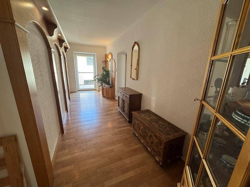 Einladende Diele mit Holzfußboden, traditionellen Möbeln und einem Spiegel an der Wand.
