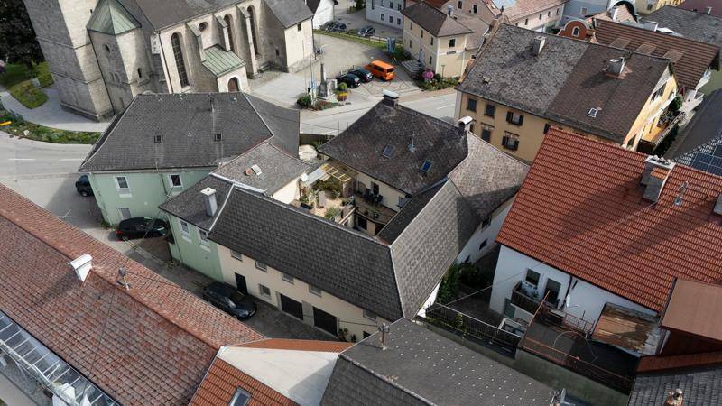 Luftaufnahme des Gebäudekomplexes mit zentraler Terrasse und Blick auf die nahegelegene Kirche.