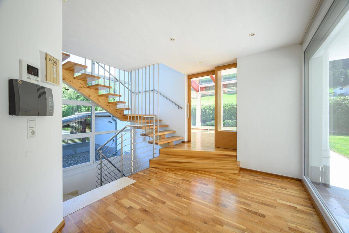 Heller Eingangsbereich mit Holztreppe und Parkettboden, der zum Garten führt.