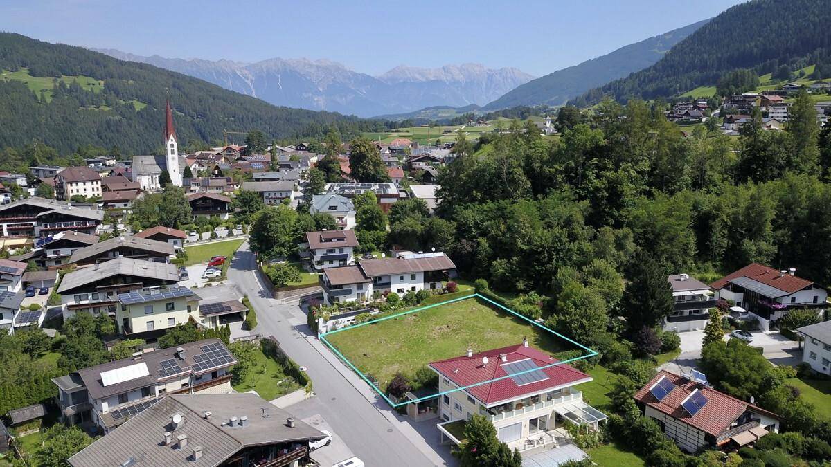 Weitläufige Luftaufnahme eines Baugrundstücks mit Bergblick und Blick auf ein charmantes Dorf.