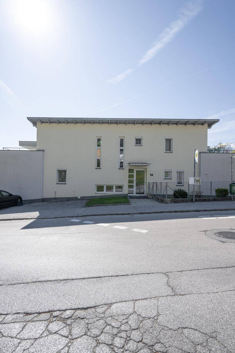 Moderne Gebäudefassade mit klaren Linien und mehreren Fenstern zur Straße.