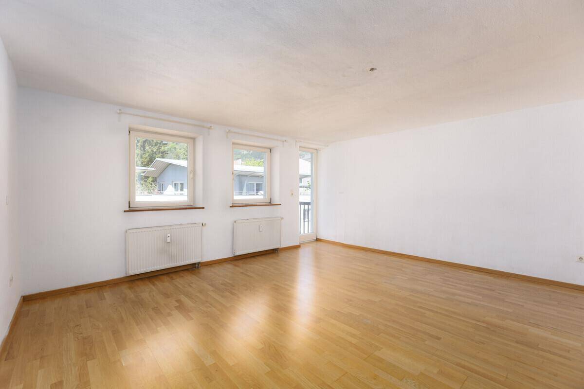 Heller Wohnraum mit Parkettboden und Zugang zu einem kleinen Balkon, ideal für frische Luft.
