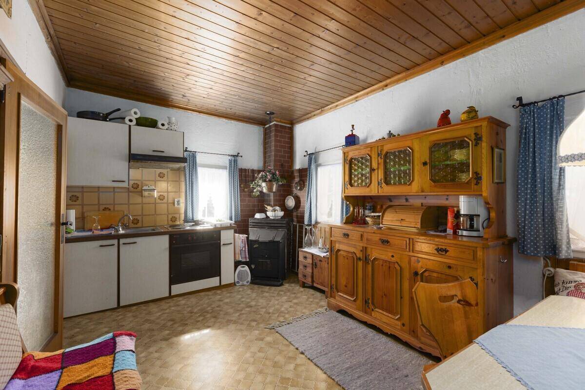 Traditionelle Küche mit Holzvertäfelung, einfacher Ausstattung und einem Holzofen.