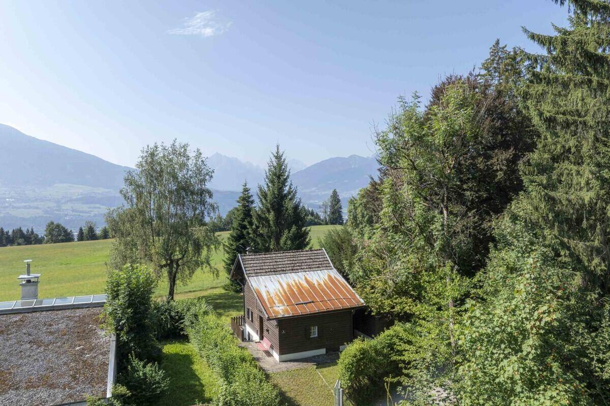 Malerisches Holzhaus eingebettet in grüne Hügel mit weitem Bergblick und viel Natur.