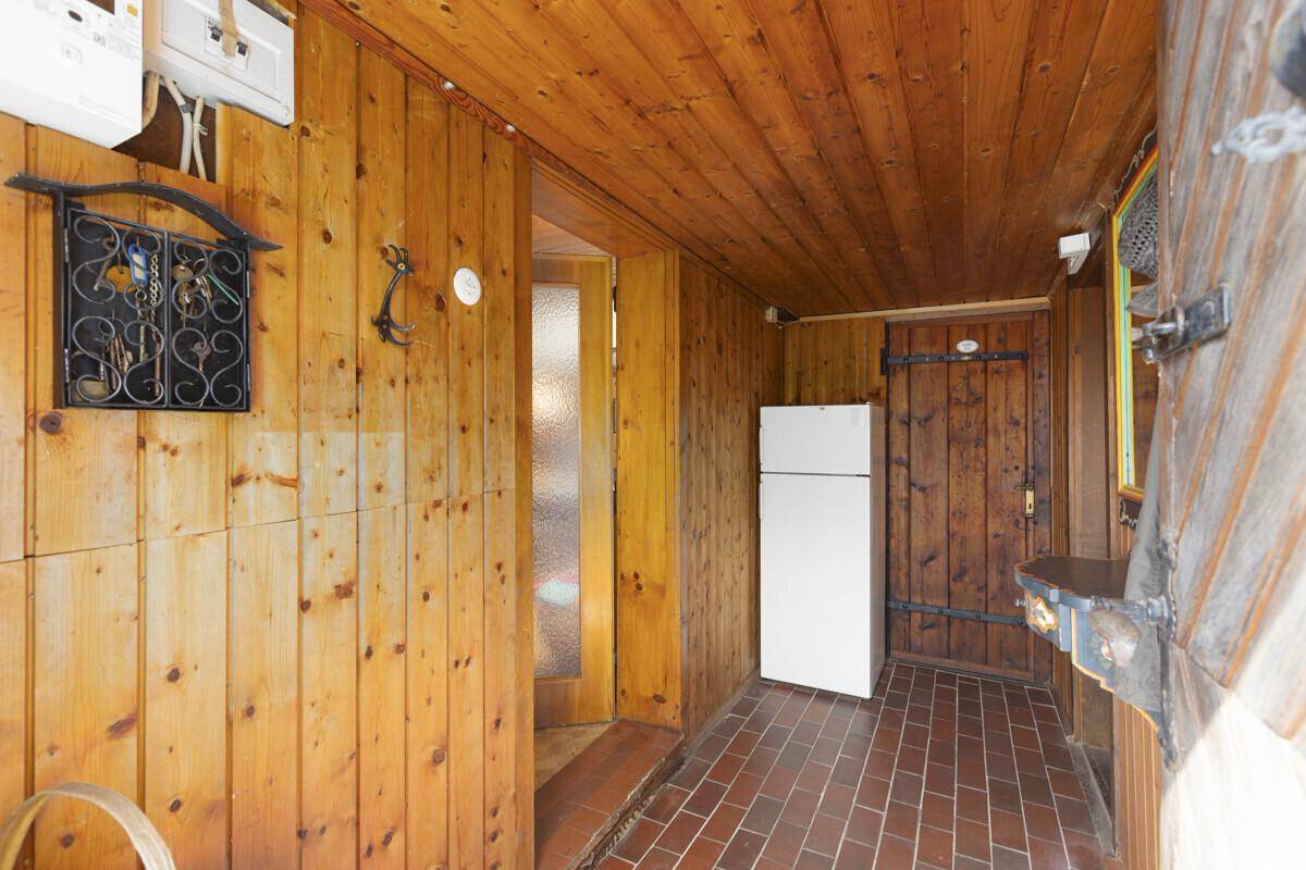 Rustikaler Eingangsbereich mit Holzvertäfelung, Fliesenboden und einem Kühlschrank.