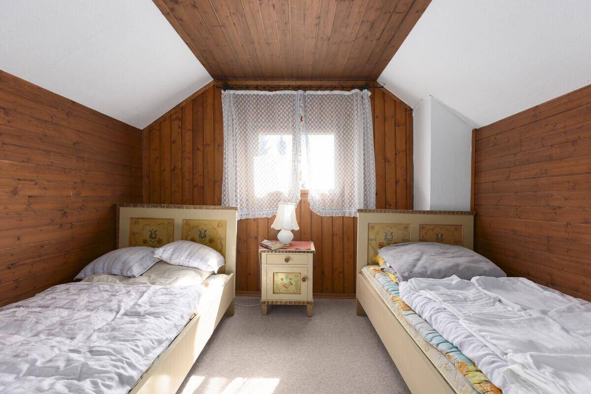 Rustikales Schlafzimmer mit zwei Einzelbetten, Holzvertäfelung und Dachschrägen.